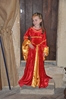 Une longue robe de princesse en velours rouge soyeux pour petite fille, doublé de tissu or.