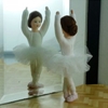 Een Erna Meyer  ballerina popje met witte tutu en lichtroze balletschoentjes kijkt in de spiegel terwijl ze de derde positie inneemt.