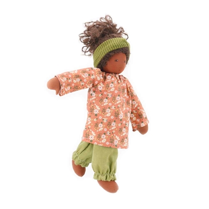 Nanchen pop 40 cm met bruine huid, bruine ogen en bruin krulhaar, abrikooskleurig kleedje, lichtgroene lange broek en lichtgroene haarband.