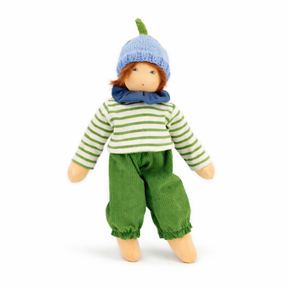 Nanchen pop met blauwe ogen en kastanjebruin haar, groene corduroy broek, een groen-wit gestreepte sweater en lichtblauwe gebreide muts met een groene steel.