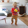 Un bambin se promène avec une balle Nanchen Natur en tissu éponge bio rouge, bleu, vert et jaune dans les mains.